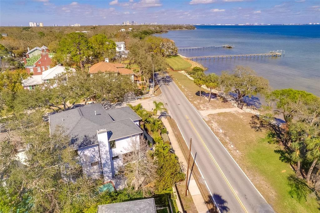 An aerial view shows a house, a coastal road, and a long wooden pier — 2802 NORTHPOINTE LANE, TAMPA, FL