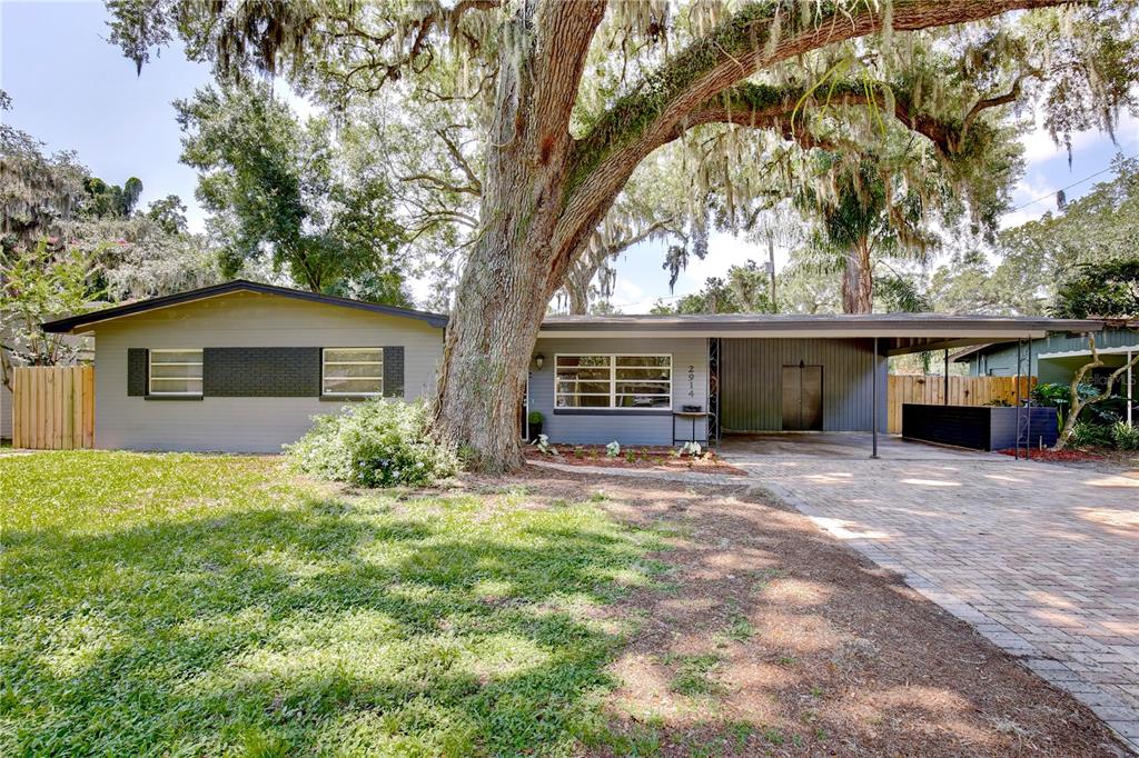 A single-story house with a gray exterior, a large oak tree, and a paved carport — 2914 LANDO LANE, ORLANDO, FL