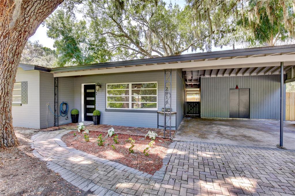 A gray single-story house features a brick walkway, a carport, and a large oak tree — 2914 LANDO LANE, ORLANDO, FL