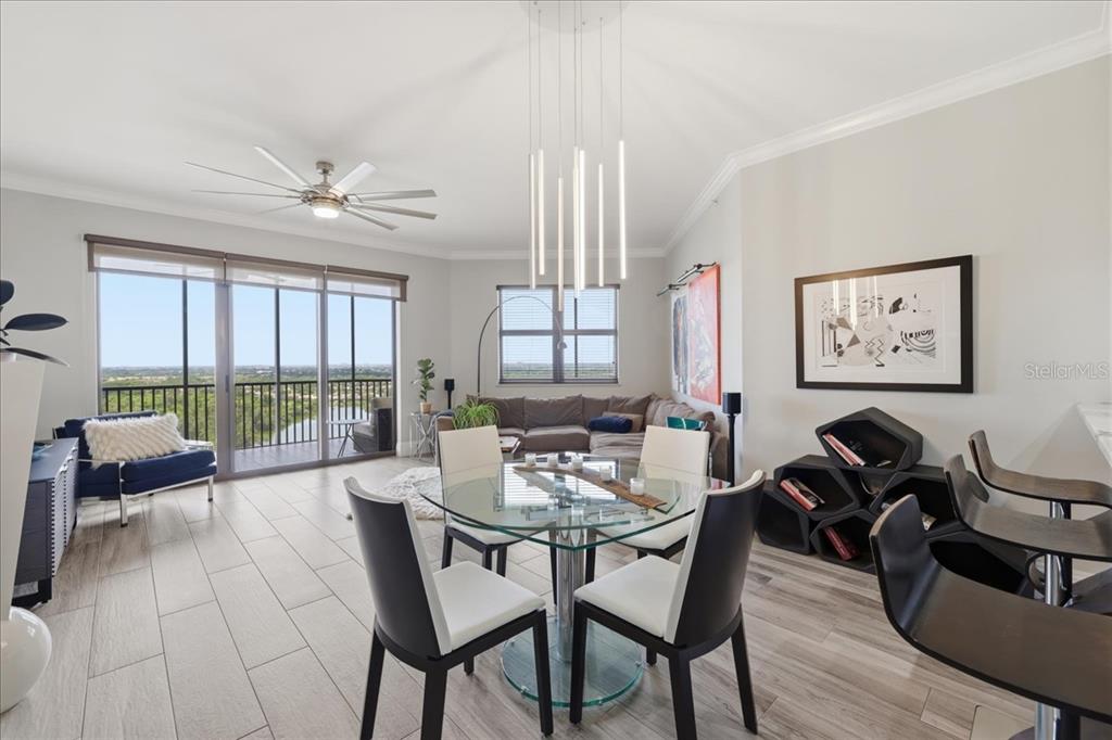 A modern dining and living area features a glass table, tile floors, and balcony views — 14300 RIVA DEL LAGO DRIVE UNIT 1802, FORT MYERS, FL