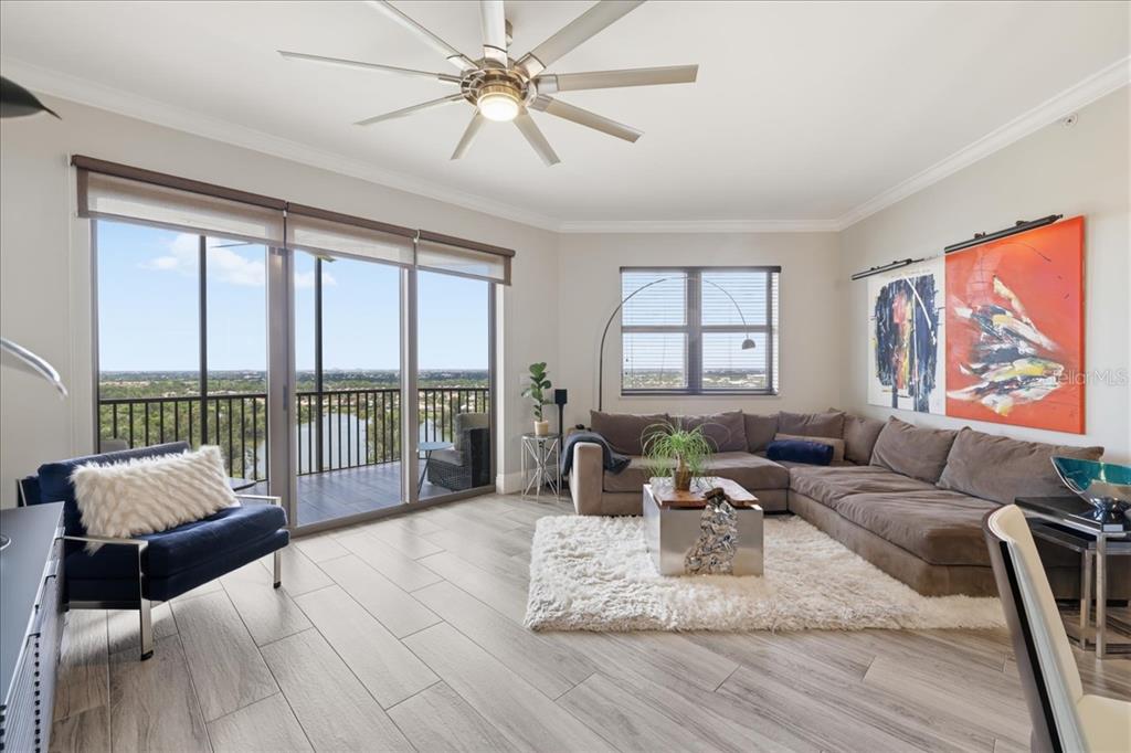 A living room features a large sectional sofa, a balcony with water views, and tile flooring — 14300 RIVA DEL LAGO DRIVE UNIT 1802, FORT MYERS, FL