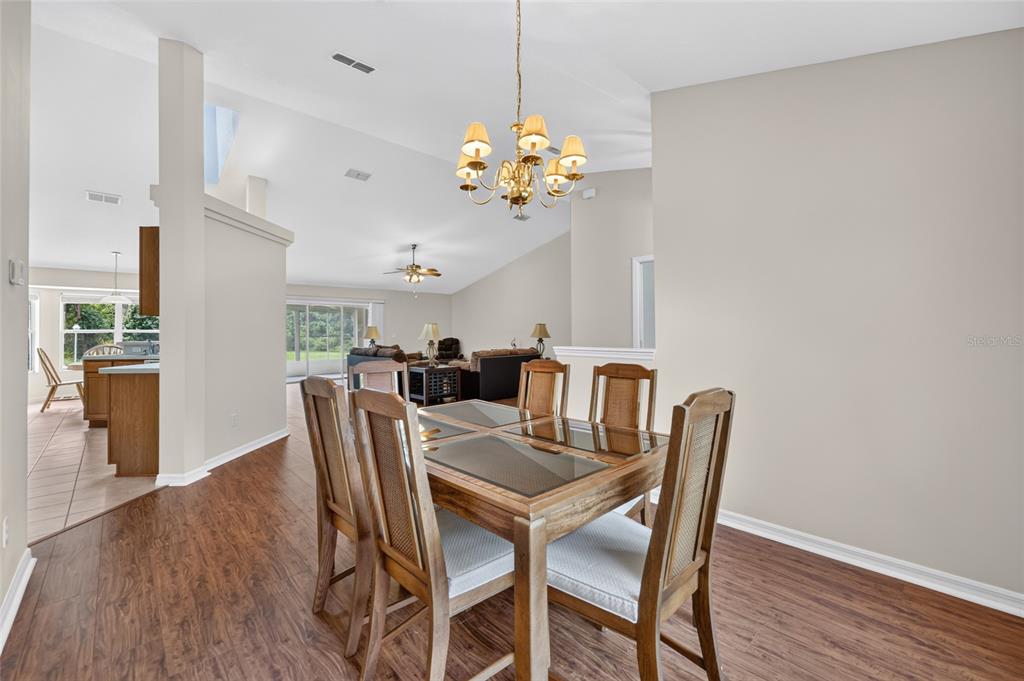 A dining area with a wood table and chairs sits before a living room space — 10976 SW 139TH COURT, DUNNELLON, FL