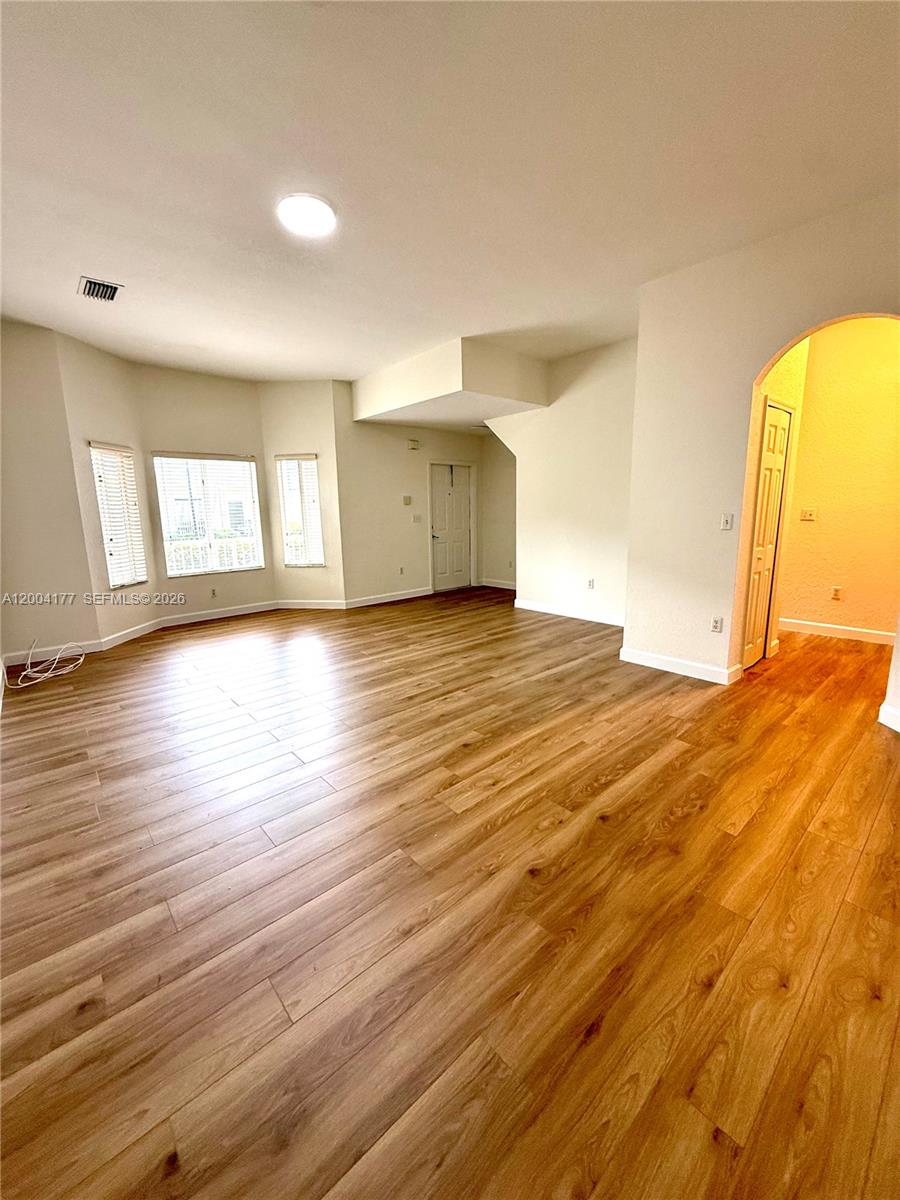 An empty living room features light wood-look flooring, white walls, and a recessed window area — 1947 SE 23rd Rd, Homestead FL 33035, HOMESTEAD, FL
