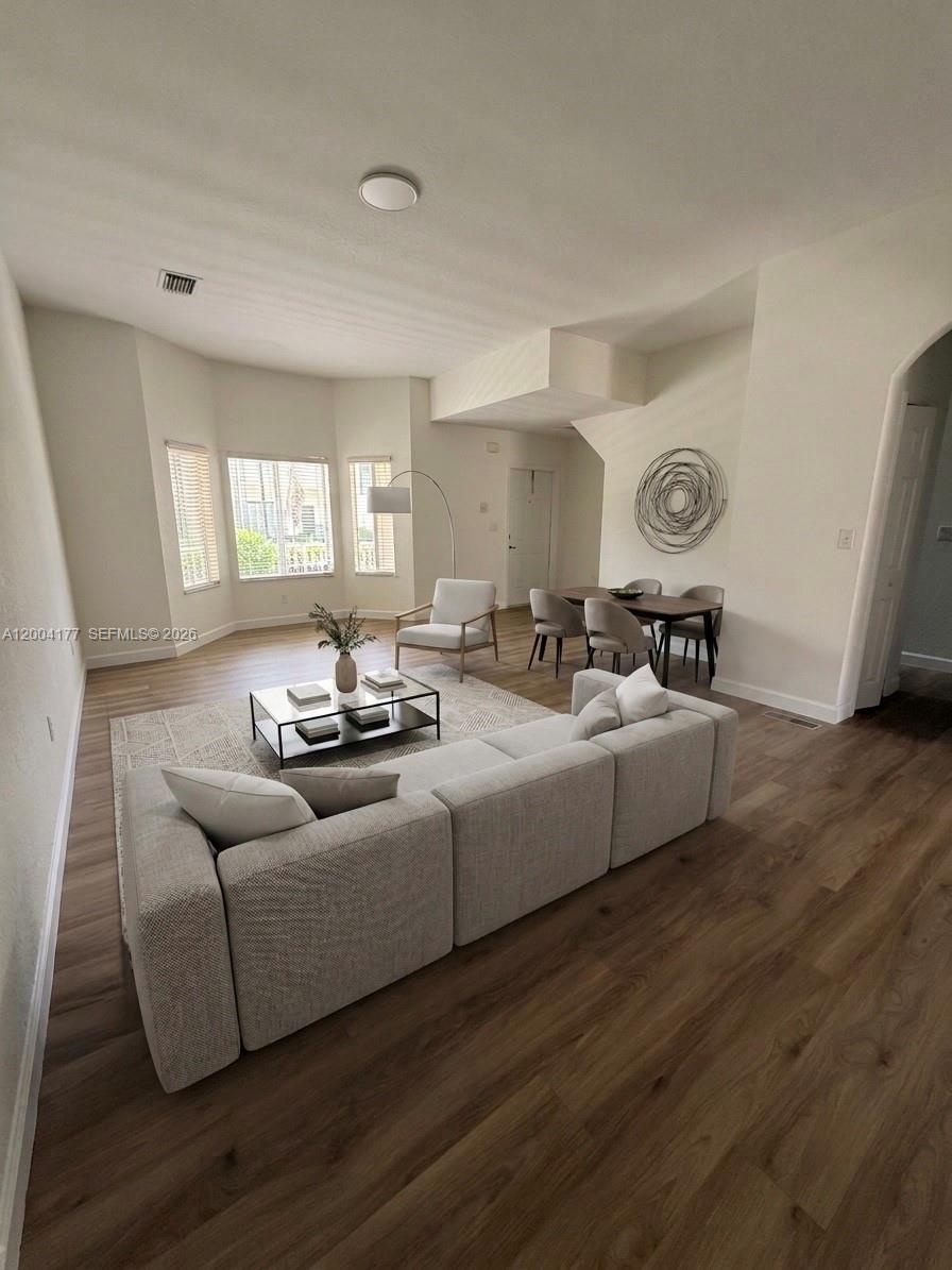 A living and dining area features light wood flooring, a sectional sofa, and bay windows — 1947 SE 23rd Rd, Homestead FL 33035, HOMESTEAD, FL