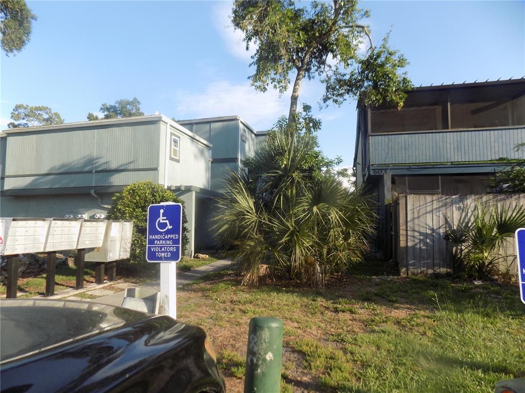 A view of apartment building exteriors with a handicapped parking sign and mailboxes in front — 613 SW 75 STREET UNIT 101, GAINESVILLE, FL