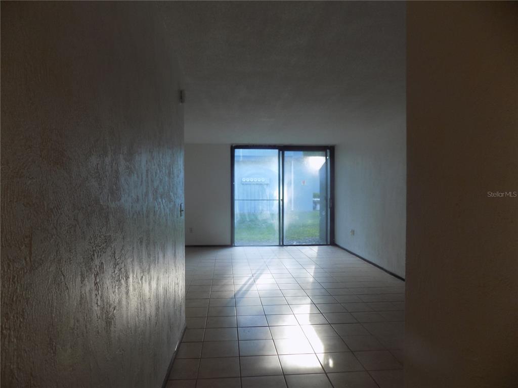 An empty room with white walls, tiled floors, and a sliding glass door to outside — 613 SW 75 STREET UNIT 101, GAINESVILLE, FL