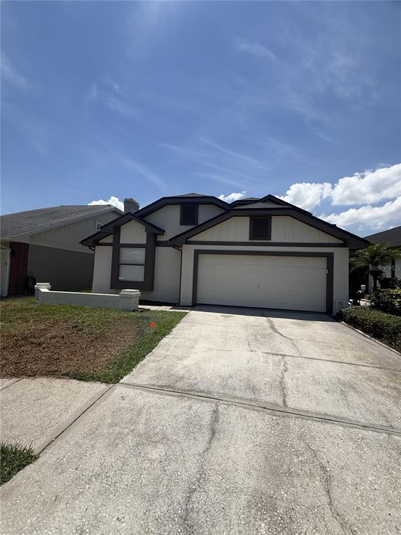 A single-story house with a two-car garage, beige siding, and a concrete driveway — 1859 SPRINGWOOD CIRCLE N, CLEARWATER, FL