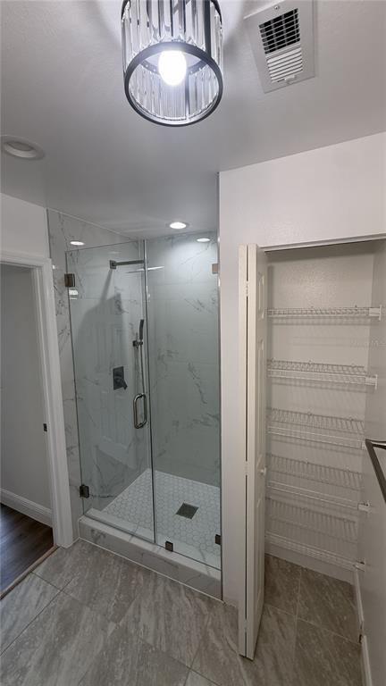A bathroom features a glass-enclosed walk-in shower with marble-look tile and a built-in linen closet — 1859 SPRINGWOOD CIRCLE N, CLEARWATER, FL