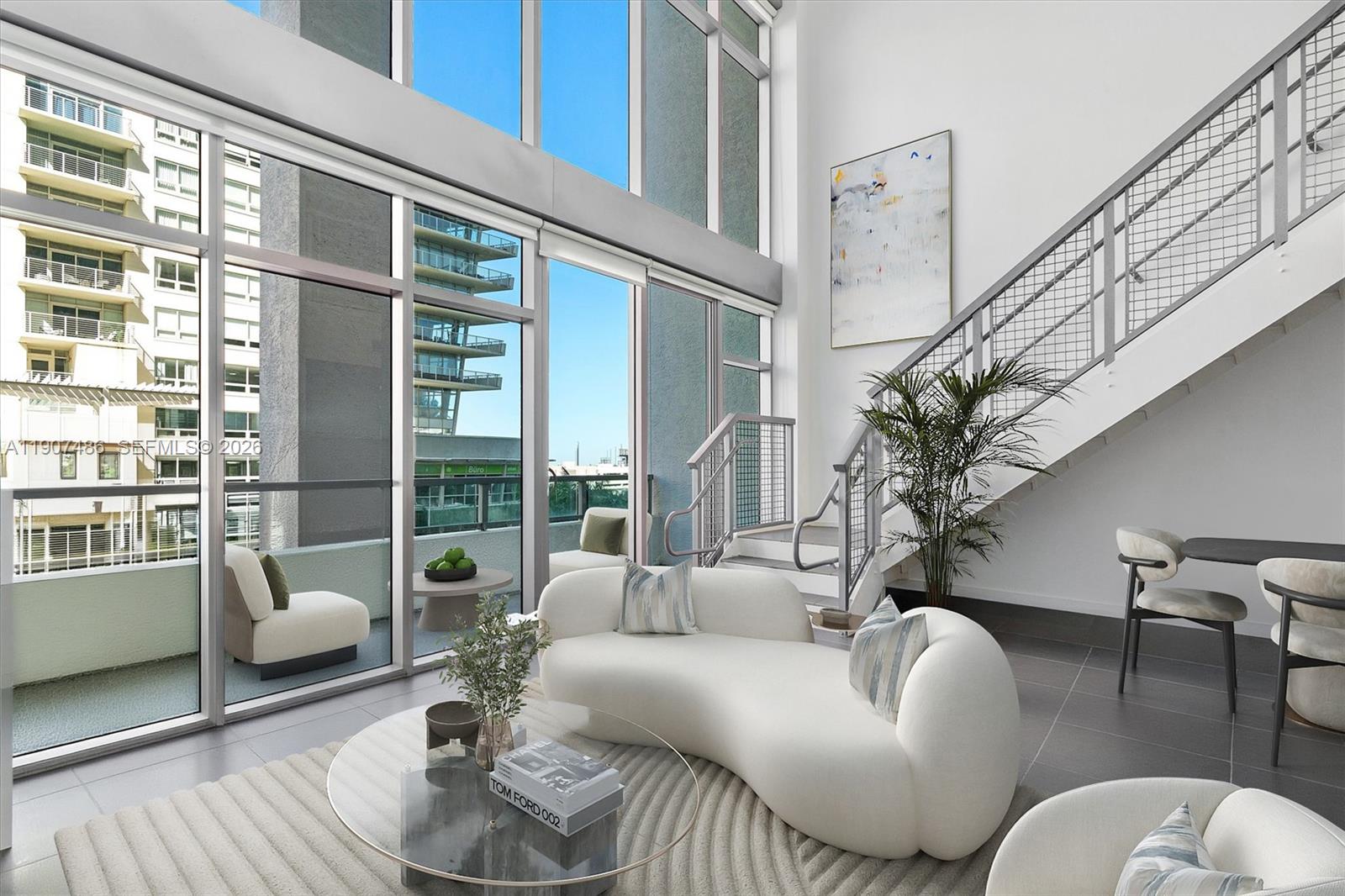 A modern living room features a curved white sofa, glass coffee table, and open kitchen — 3301 NE 1st Ave # M0502, Miami FL 33137, MIAMI, FL