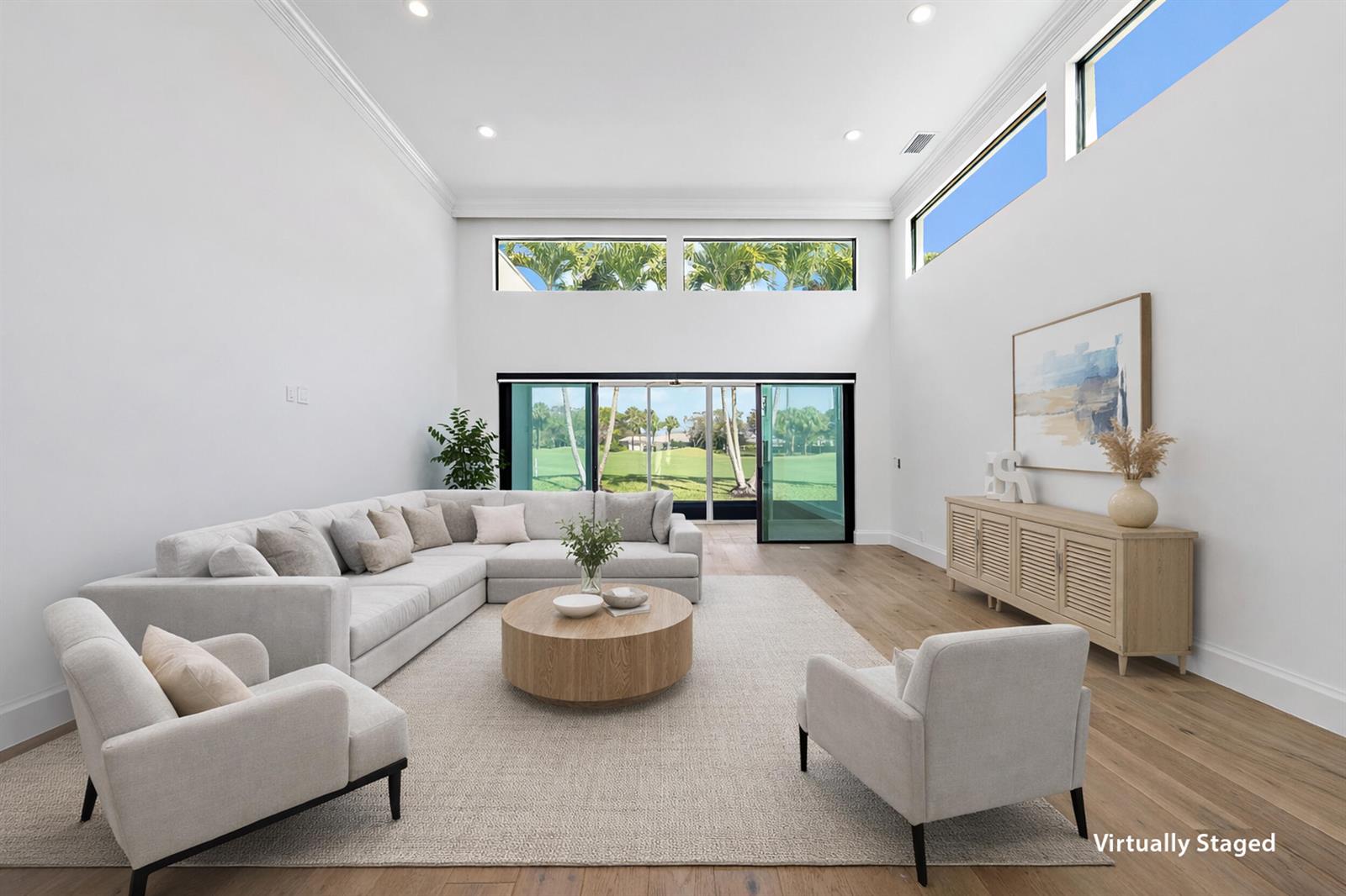 A bright living room features high ceilings, light wood floors, and large glass sliding doors — 108 Waters Edge Drive, Jupiter FL 33477, JUPITER, FL