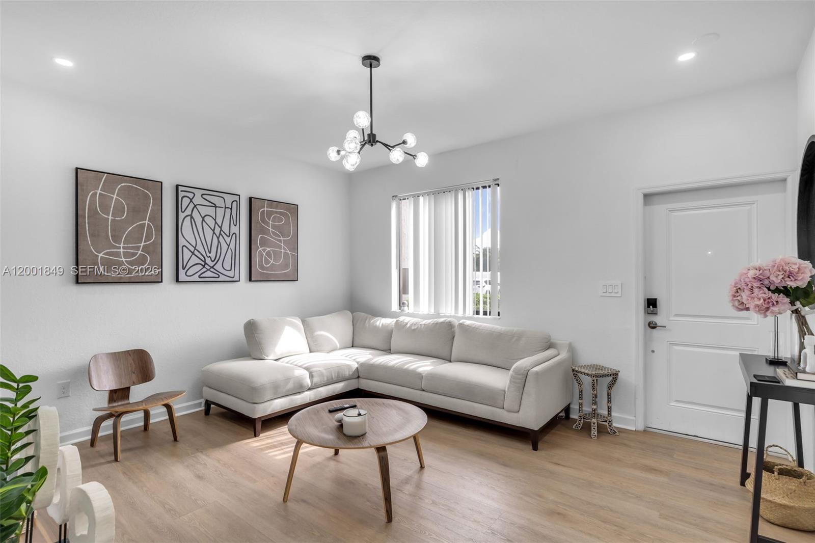 A living room features a white sectional sofa, a round wooden coffee table, and wall art — 21444 NE 2nd Path, Miami FL 33179, MIAMI, FL
