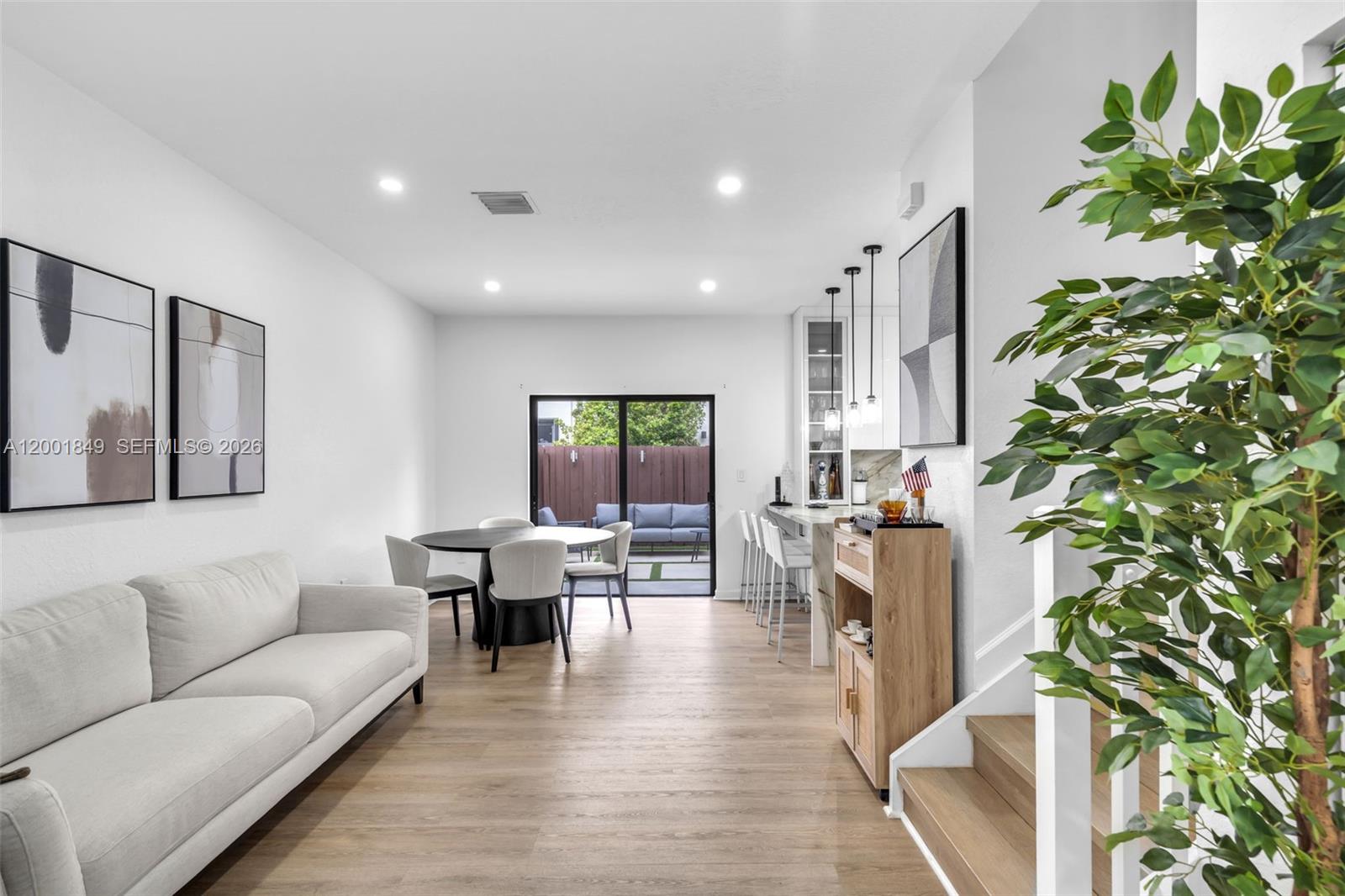A modern living and dining area features light wood flooring, a sofa, and a bar — 21444 NE 2nd Path, Miami FL 33179, MIAMI, FL