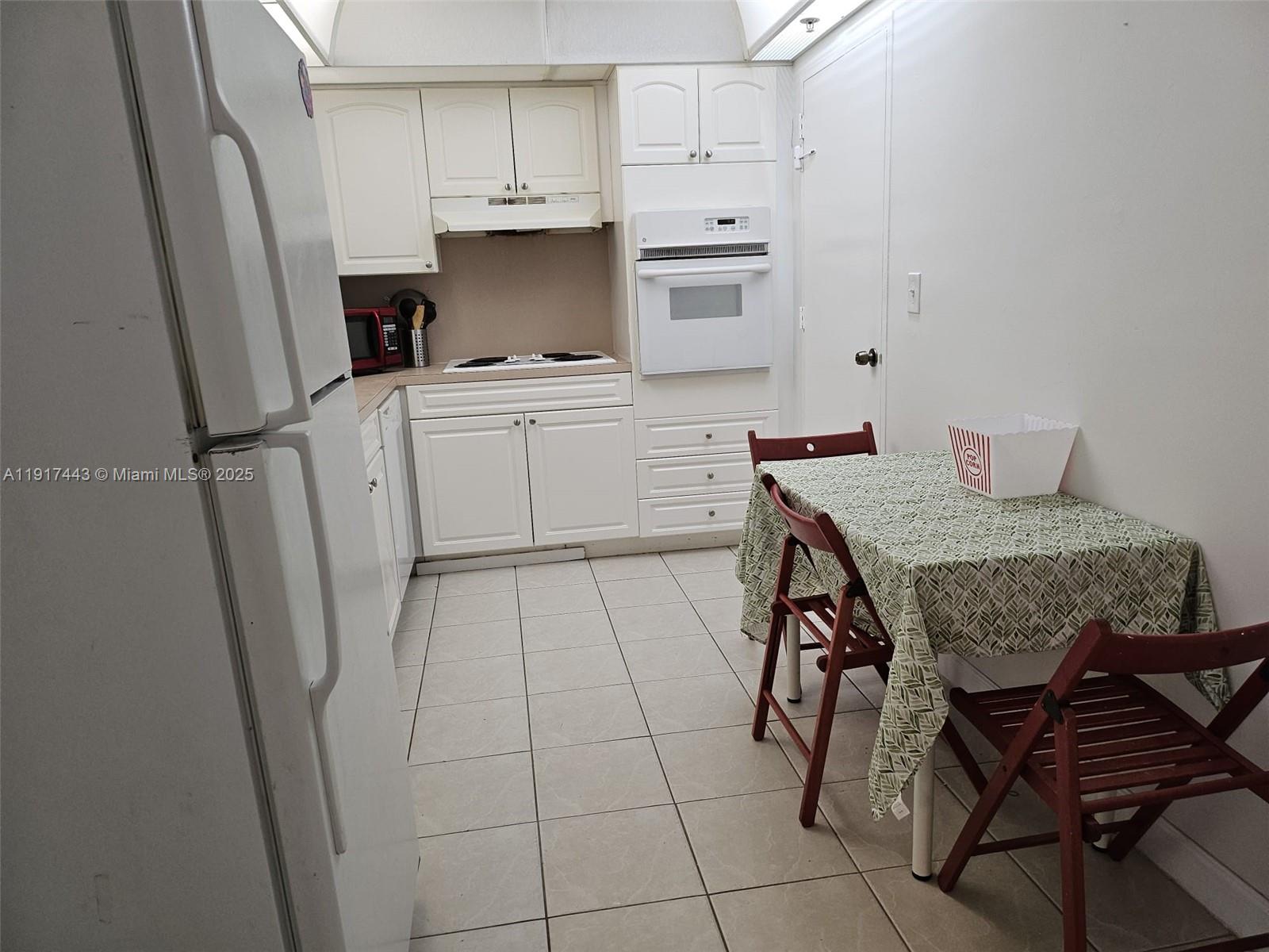 A kitchen features white cabinetry, a built-in wall oven, a cooktop, and a small dining table — 4001 S OCEAN DR # 7F, Hollywood FL 33019, HOLLYWOOD, FL