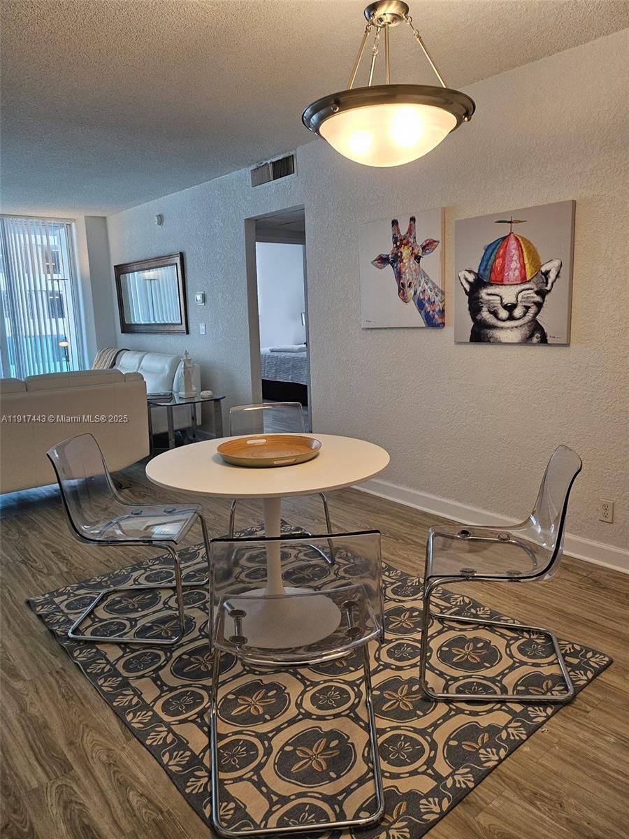 A dining area features a round white table, clear chairs, and whimsical animal wall art — 4001 S OCEAN DR # 7F, Hollywood FL 33019, HOLLYWOOD, FL