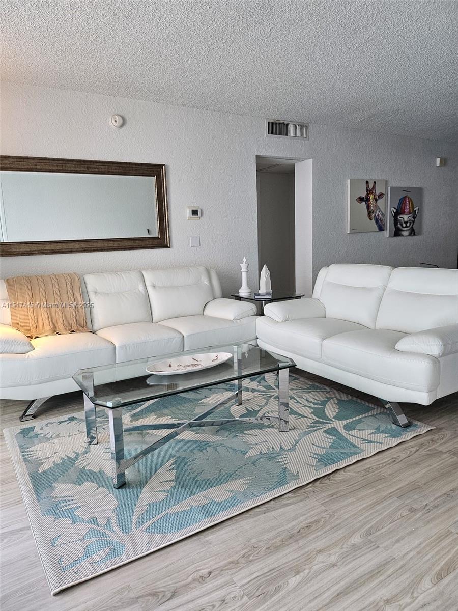 A living room features white leather sofas, a glass coffee table, and a patterned rug — 4001 S OCEAN DR # 7F, Hollywood FL 33019, HOLLYWOOD, FL