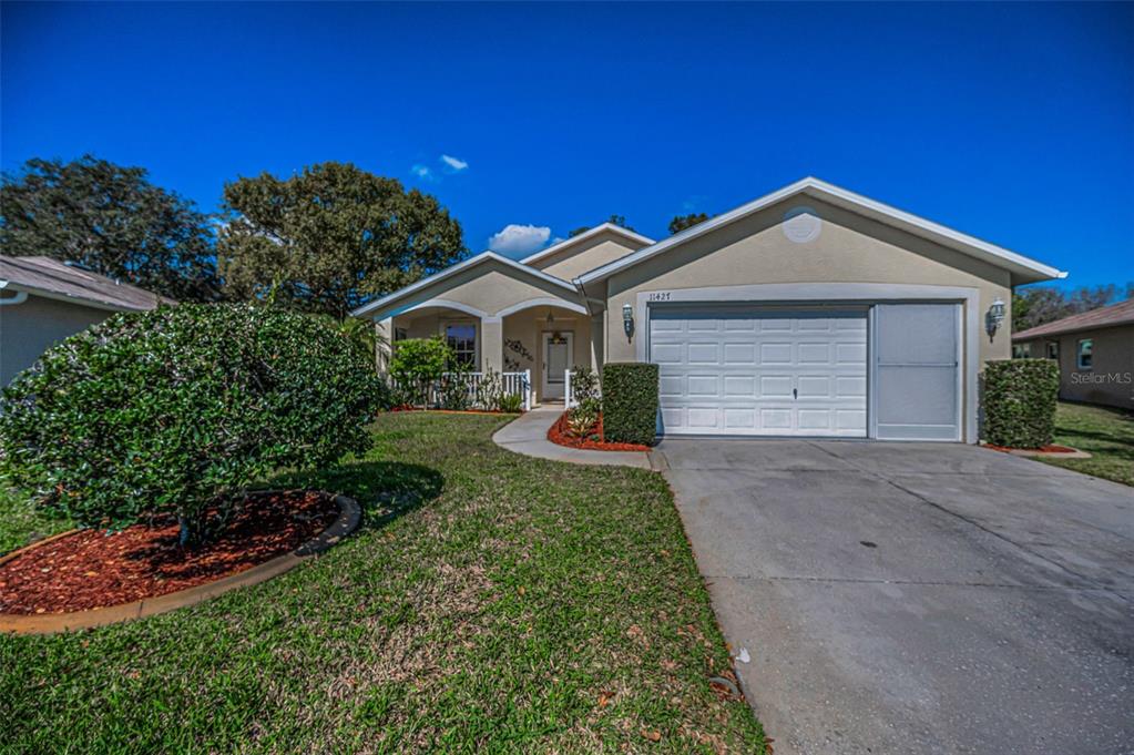 A single-story house with a beige stucco exterior, a two-car garage, and a front lawn — 11427 TURTLE DOVE PLACE, NEW PORT RICHEY, FL