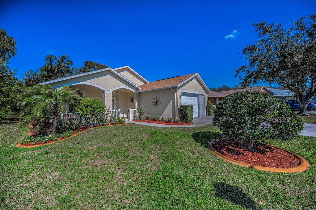 A single-story house with a tan exterior, a front porch, and a one-car garage — 11427 TURTLE DOVE PLACE, NEW PORT RICHEY, FL