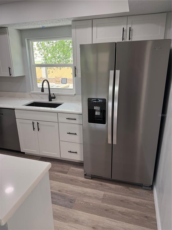 A kitchen features white cabinets, a stainless steel refrigerator, and a black sink — 439 76TH AVENUE N, ST PETERSBURG, FL