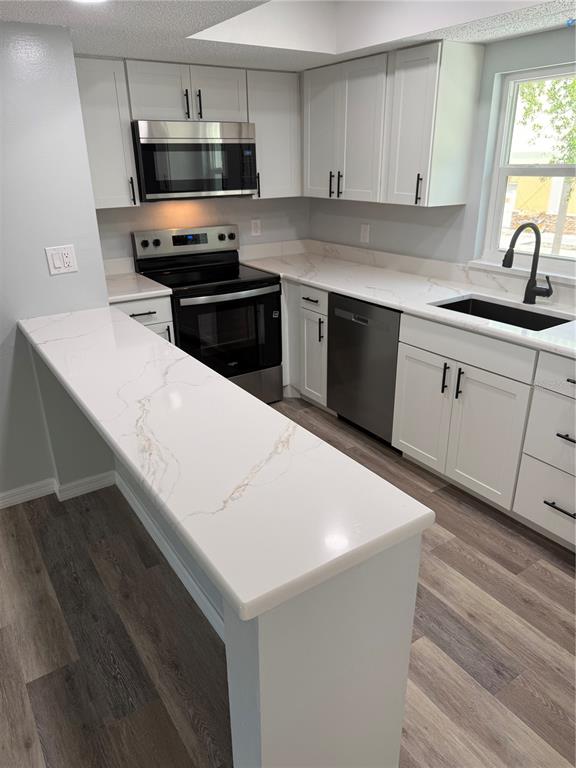 A kitchen features white cabinets, stainless steel appliances, and a white marble-look countertop peninsula — 439 76TH AVENUE N, ST PETERSBURG, FL