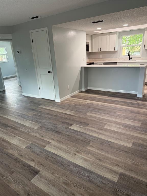 A room with wood-look vinyl flooring, a white door, and a kitchen with a breakfast bar — 439 76TH AVENUE N, ST PETERSBURG, FL