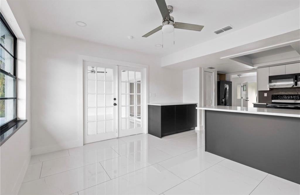 A bright dining area features white tile floors, a ceiling fan, and French doors — 3381 MINNOW CREEK DRIVE, HERNANDO BEACH, FL