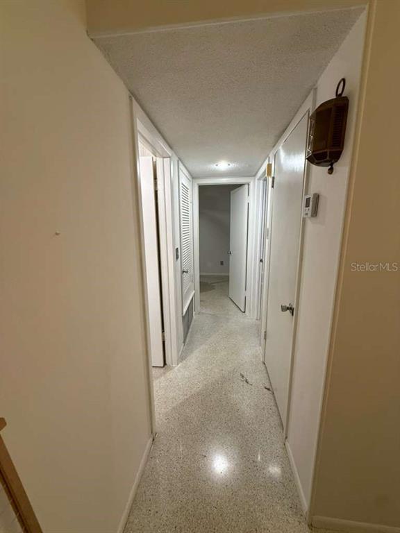 A narrow hallway with white walls, a light-colored terrazzo floor, and several closed interior doors — 21385 GIBRALTER DRIVE, PORT CHARLOTTE, FL