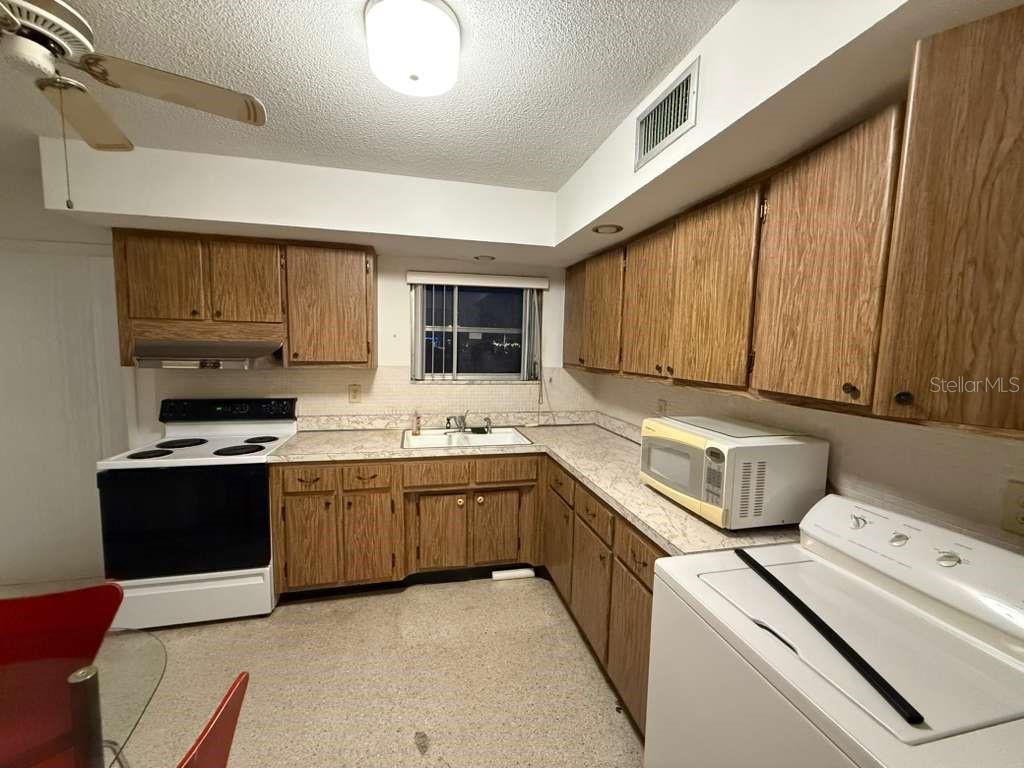A kitchen with wood cabinets, white appliances, a ceiling fan, and a window above the sink — 21385 GIBRALTER DRIVE, PORT CHARLOTTE, FL