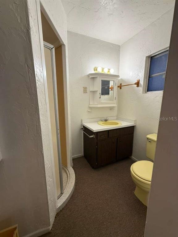 A bathroom features a dark wood vanity, a yellow toilet, and a corner shower stall — 21385 GIBRALTER DRIVE, PORT CHARLOTTE, FL