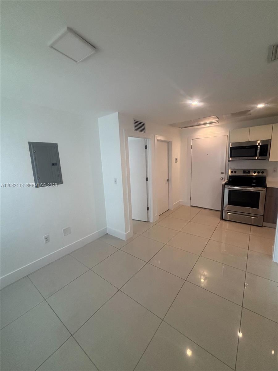 A kitchen and living area with white walls, tile flooring, and stainless steel appliances — 821 SW 18th Ave # 203, Miami FL 33135, MIAMI, FL