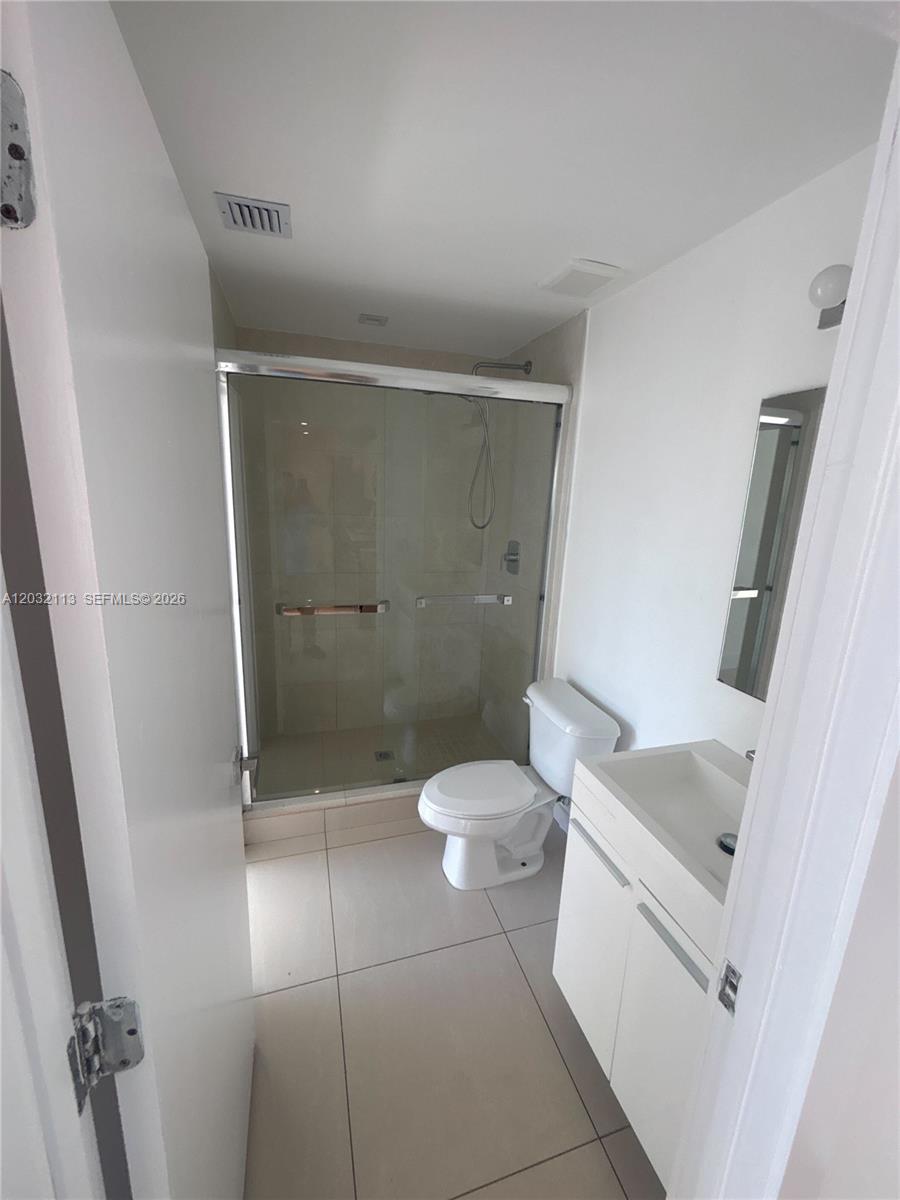 This bathroom features a glass-enclosed shower, a white vanity, and light-colored floor tiles — 821 SW 18th Ave # 203, Miami FL 33135, MIAMI, FL