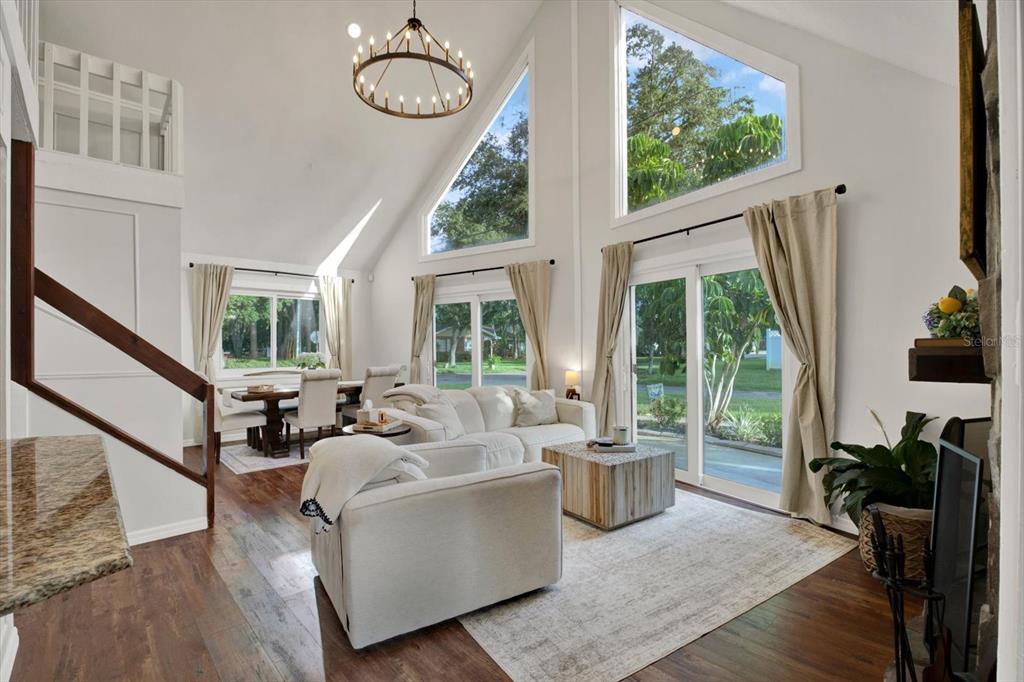 A living room with vaulted ceilings, large windows, a chandelier, and hardwood floors — 7295 HUBERT STREET, SEMINOLE, FL