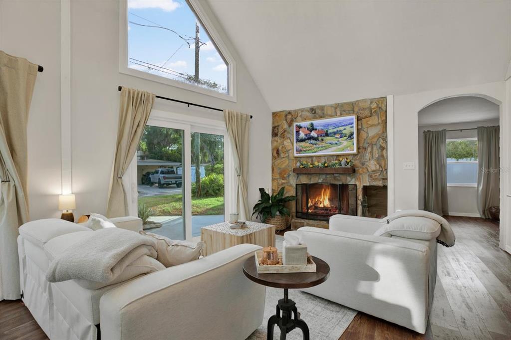 A living room features a stone fireplace, vaulted ceilings, and sliding glass doors to outside — 7295 HUBERT STREET, SEMINOLE, FL