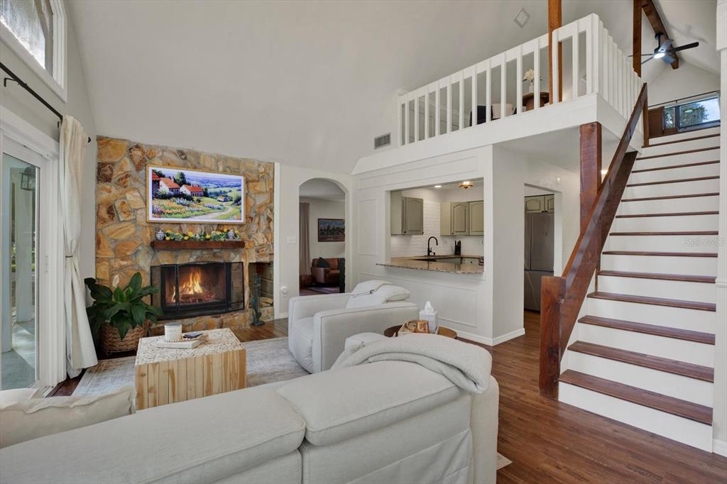 A living room features a stone fireplace, a loft area, and a staircase — 7295 HUBERT STREET, SEMINOLE, FL