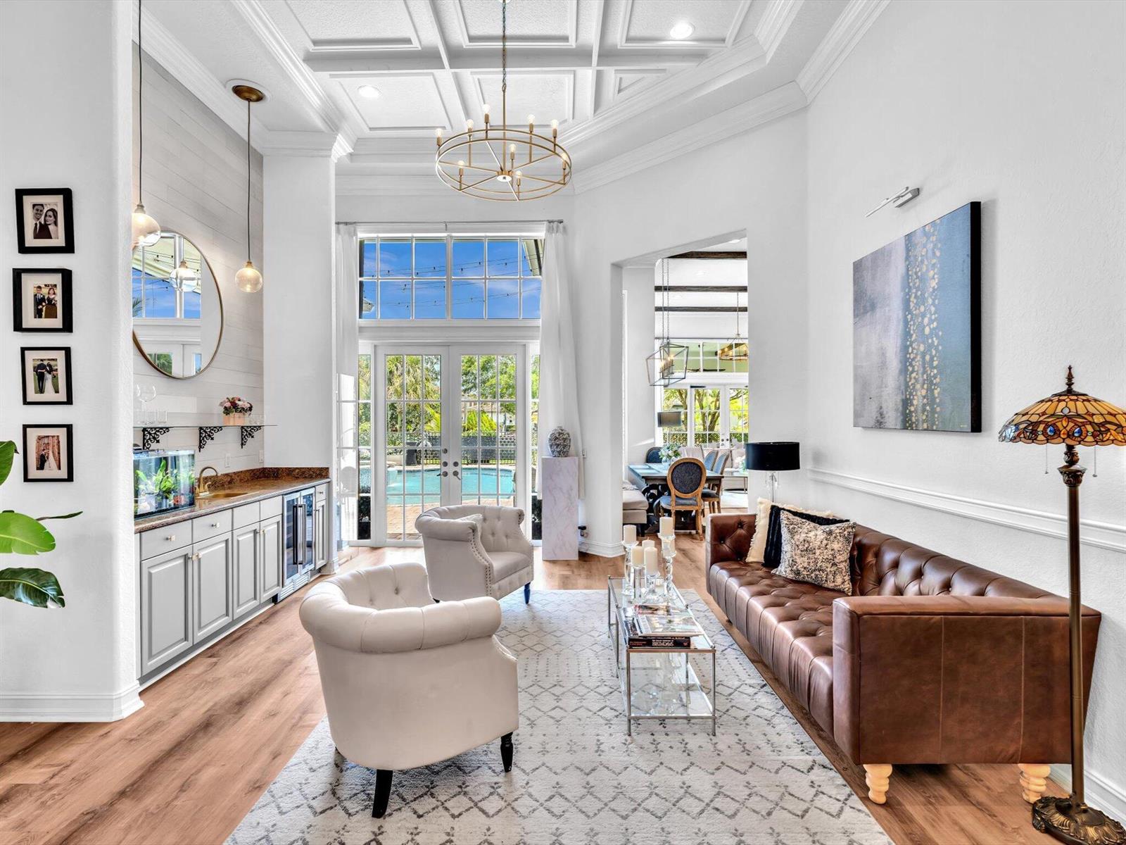 A living room with a brown leather sofa, two white armchairs, and a wet bar — 7738 NW 112th Way, Parkland FL 33076, PARKLAND, FL