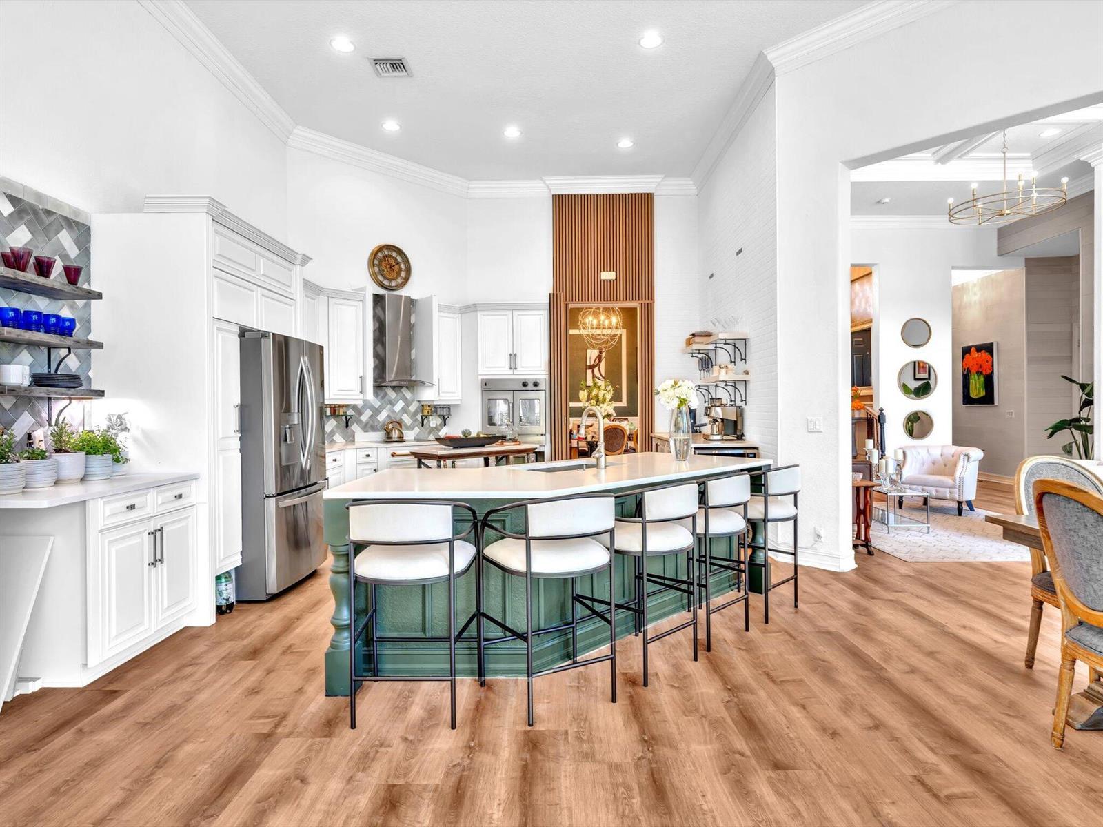 A kitchen with a green island, white cabinetry, and wood-look flooring — 7738 NW 112th Way, Parkland FL 33076, PARKLAND, FL