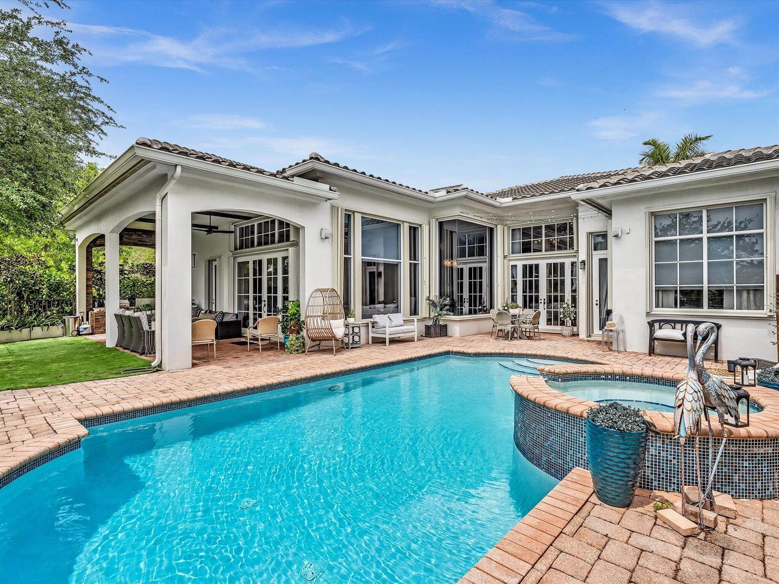 A backyard swimming pool and hot tub sit on a brick patio beside a house — 7738 NW 112th Way, Parkland FL 33076, PARKLAND, FL