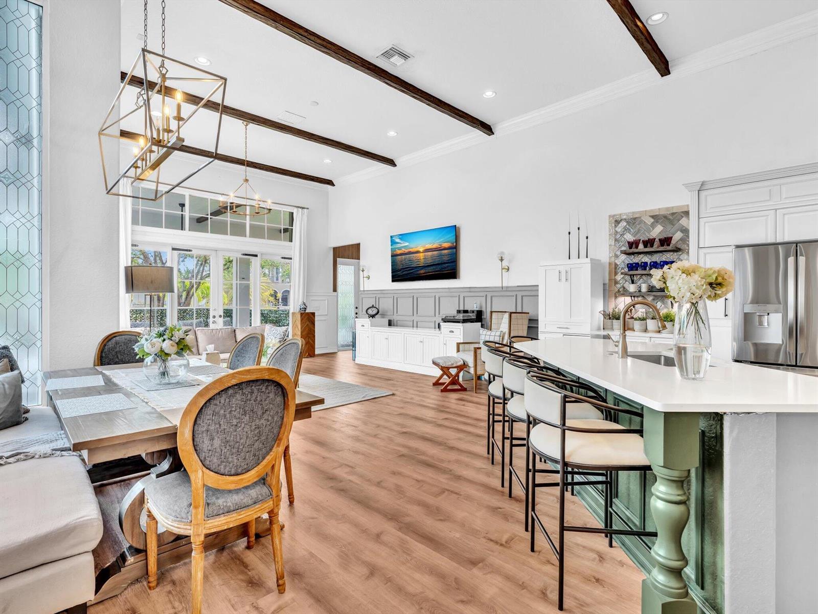 A bright, open-concept kitchen and dining area features wood-look flooring, exposed ceiling beams, and cabinetry — 7738 NW 112th Way, Parkland FL 33076, PARKLAND, FL