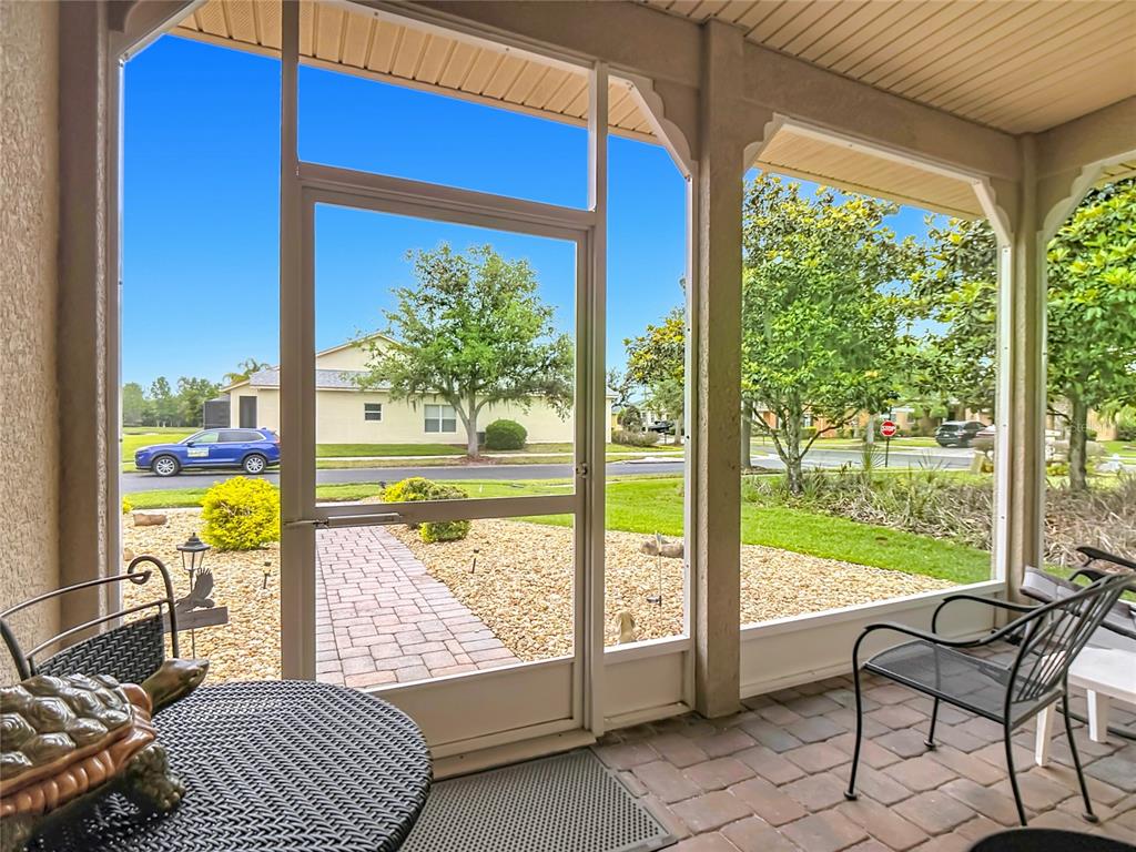 A screened-in porch with a brick paver floor overlooks a suburban street and lawn — 107 VERONA DR, KISSIMMEE, FL