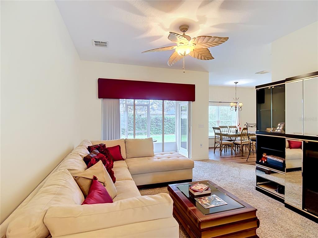 A living room with a sectional sofa and coffee table opens to a dining area — 107 VERONA DR, KISSIMMEE, FL