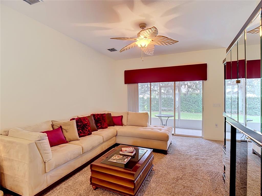 A living room features a beige sectional sofa, a coffee table, and a sliding glass door — 107 VERONA DR, KISSIMMEE, FL