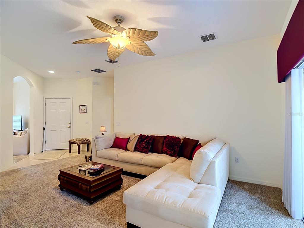 A living room features a beige sectional sofa, a wooden coffee table, and a ceiling fan — 107 VERONA DR, KISSIMMEE, FL