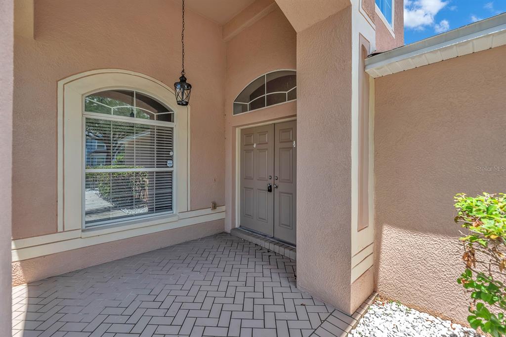 A paved entryway features a double front door, an arched window, and a hanging lantern — 10904 SUMMERTON DRIVE, RIVERVIEW, FL