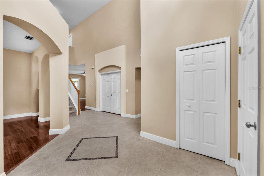 An interior view of a foyer with tile flooring, high ceilings, and white paneled doors — 10904 SUMMERTON DRIVE, RIVERVIEW, FL
