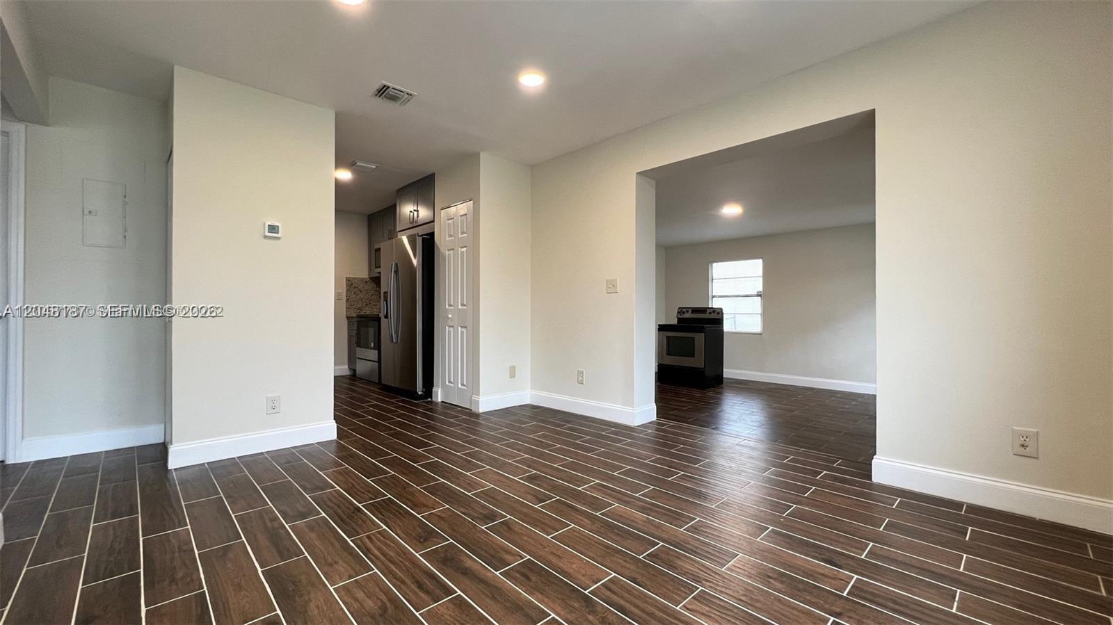 An interior view shows a dining area with wood-look tile floors leading to a kitchen — 2130 Funston St # 2130, Hollywood FL 33020, HOLLYWOOD, FL