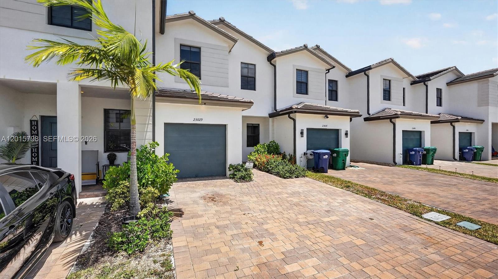 A row of modern townhouses features white stucco exteriors, paver driveways, and attached garages — 23029 SW 128th Pl, Miami FL 33170, MIAMI, FL