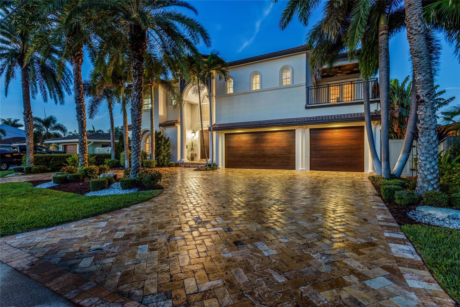 A two-story house with a paved driveway, two garage doors, and palm trees at dusk — 3489 NE 30th Avenue, Lighthouse Point FL 33064, LIGHTHOUSE POINT, FL