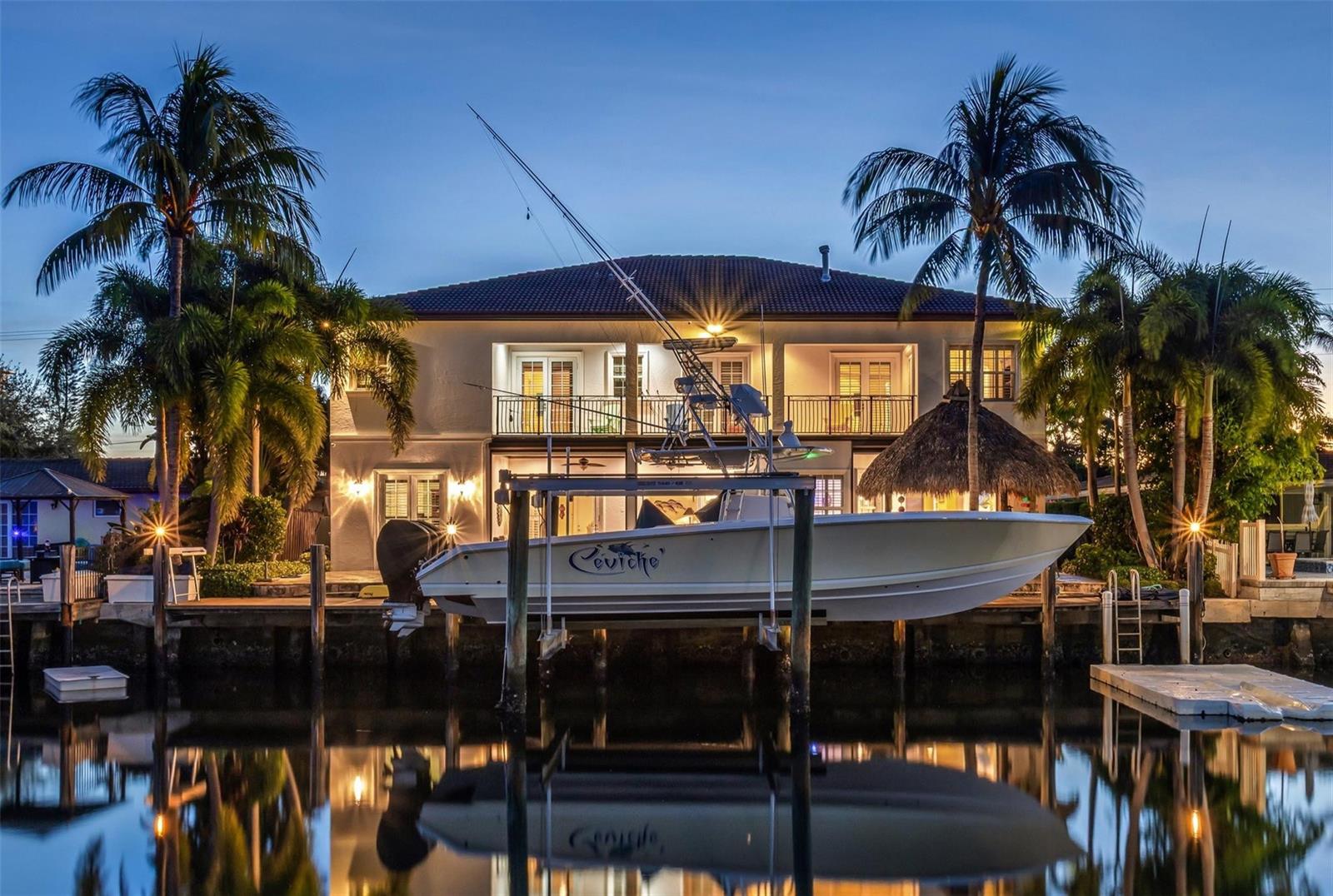 A boat on a lift sits in a canal in front of a two-story house — 3489 NE 30th Avenue, Lighthouse Point FL 33064, LIGHTHOUSE POINT, FL