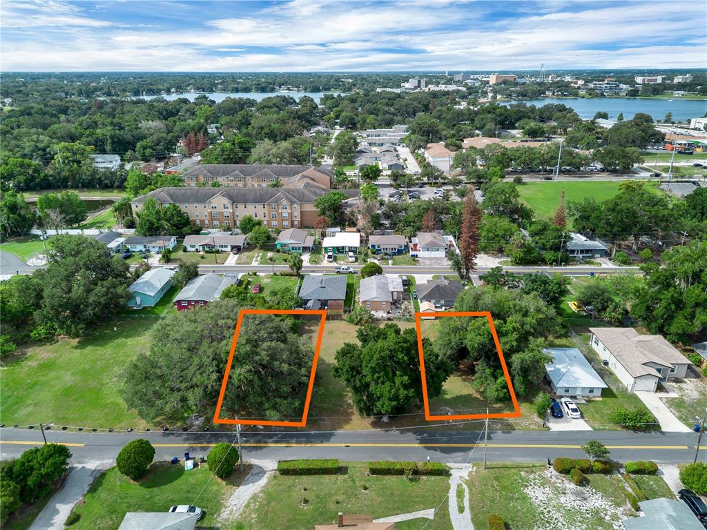 An aerial view shows two adjacent vacant lots outlined in orange along a paved road — 223 PALMETTO AVENUE NE, WINTER HAVEN, FL