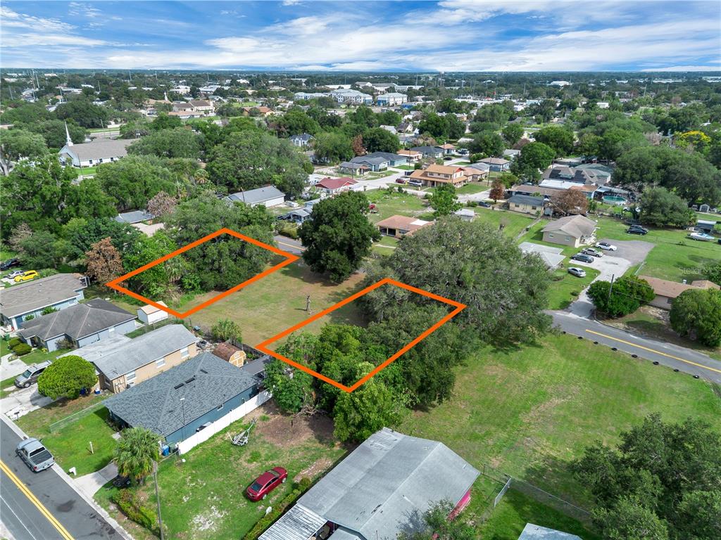 An aerial view shows two vacant, tree-covered residential lots outlined in orange within a neighborhood — 223 PALMETTO AVENUE NE, WINTER HAVEN, FL