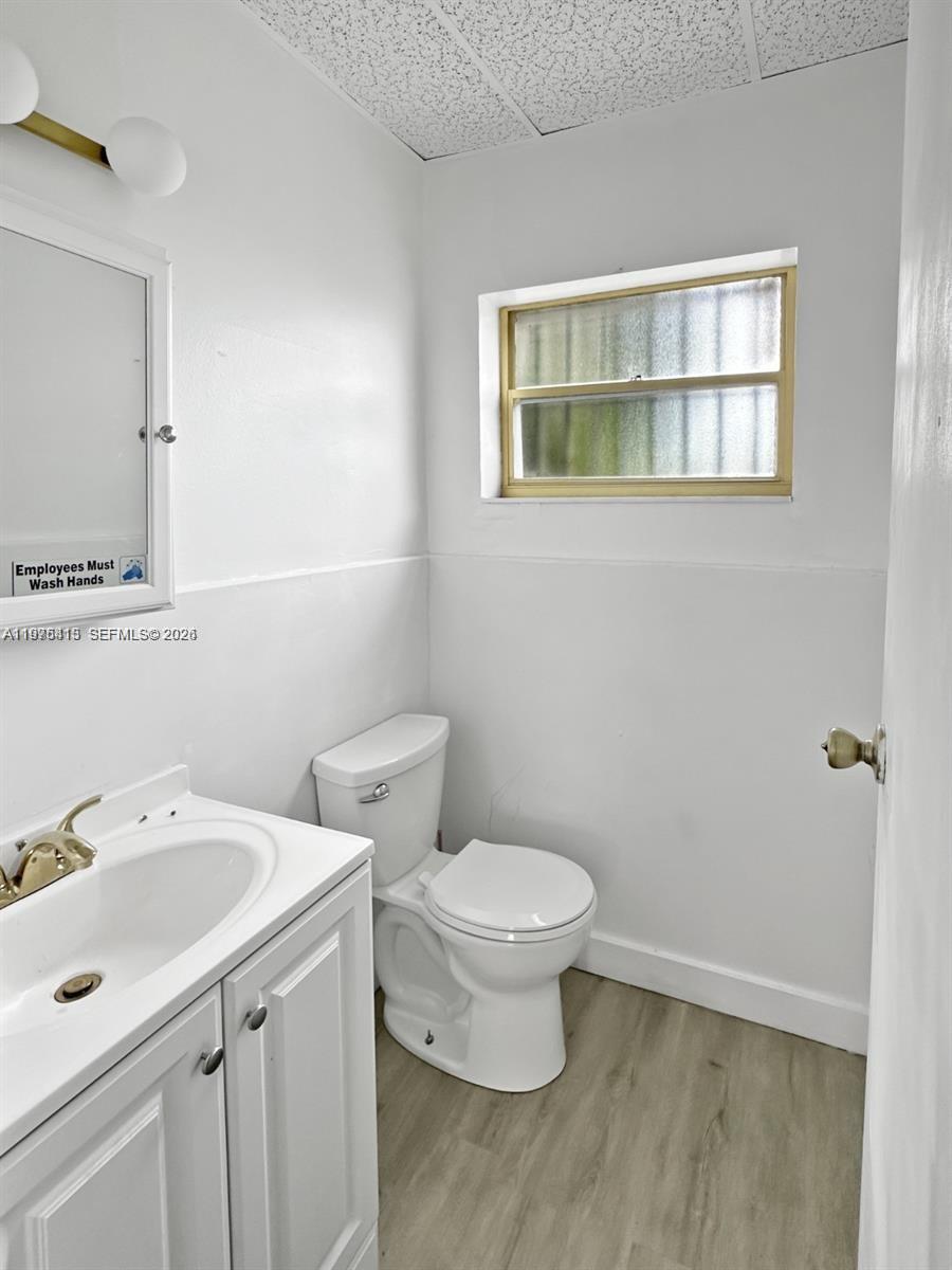 A small bathroom features a white vanity, a toilet, and a window with frosted glass — 497 NW 27th Ave # 497, Miami FL 33125, MIAMI, FL